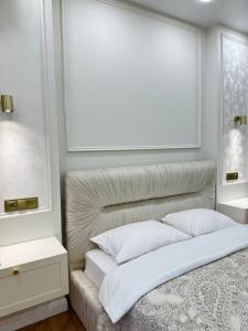 a white bedroom with a bed with white pillows at NBG d 'amore Appart in Batumi