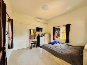 a bedroom with a bed and a desk and a refrigerator at ตาแอกะยายแดงโฮมสเตย์ in Ban Hong Khu