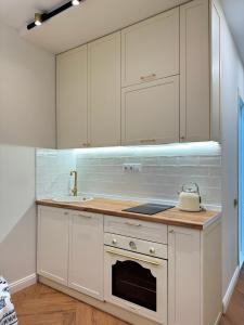 a kitchen with white cabinets and a sink at NBG d 'amore Appart in Batumi