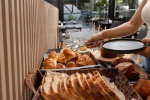 a person reaching for a tray of bread and pastries at Hotel Gema Luxury Suites in Montevideo