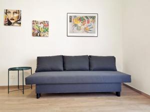 a blue couch in a room with paintings on the wall at L'altro Krisà in Bari