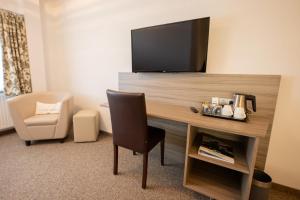 a room with a desk with a television and a chair at Cuxlandhotel Studio 203 in Dorum Neufeld +20 photos