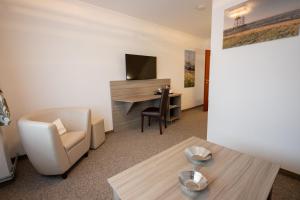 a living room with a chair and a desk at Cuxlandhotel Studio 203 in Dorum Neufeld