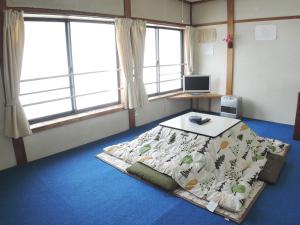 a room with a bed and a desk and two windows at Sendaiya in Hida