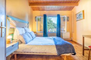 a bedroom with a bed with blue curtains and a window at Maison 250m plage - grand jardin in L'Ile d'Yeu