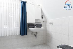 a bathroom with a sink and a blue shower curtain at Töwerland Zimmer 7 in Juist +10 photos