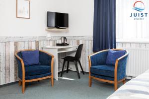 2 stoelen en een bureau in een hotelkamer bij Töwerland Zimmer 2 in Juist