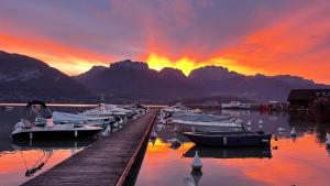 a group of boats docked at a dock with a sunset at Le Chalet de la Plage in Sévrier