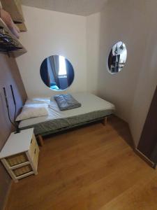a small room with a bed and two mirrors at Appartement VUE SUR LES MONTAGNES in Saint-Pierre-de-Chartreuse