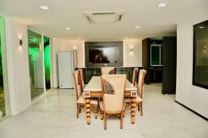 a dining room with a table and chairs and a television at Cozycasa By Nattis group 4 BR - Jacuzzi & private garden in Kondapur