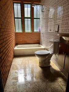 a bathroom with a toilet and a bath tub at Quarto privado completo in Botucatu +24 photos