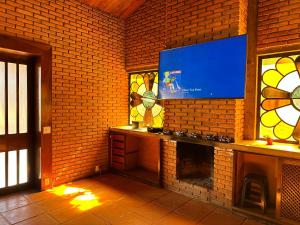 a room with a fireplace with a tv on a brick wall at Quarto privado completo in Botucatu