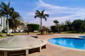 a pool in a park with a bench and palm trees at Cozycasa By Nattis group 4 BR - Jacuzzi & private garden in Kondapur