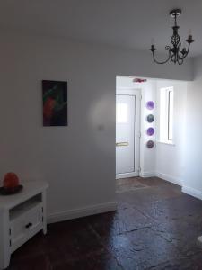 a room with white walls and a table and a chandelier at The Wild Atlantic Neurodiversity Autism Sanctuary in Miltown Malbay