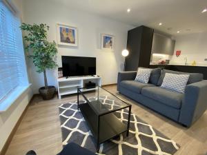 a living room with a couch and a tv at Roomspace Serviced Apartments - Harvest Lane in Thames Ditton +15 photos