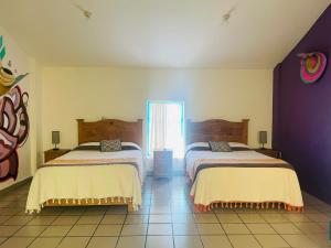 Dos camas en una habitación con paredes moradas. en San Cristóbal Bleisure Hotel Centro, en San Cristóbal de Las Casas 38 fotos más