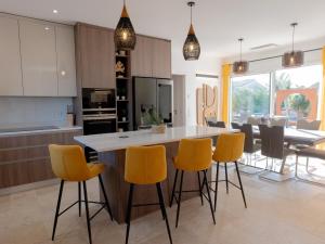 eine Küche mit gelben Stühlen und eine Kücheninsel in der Unterkunft Villa Harmonie - Luxe, Jaccuzzi et Piscine en Charente-maritime in Saint-Ciers-du-Taillon