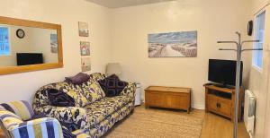 a living room with a couch and a tv at Rockpool Cottage in Beadnell
