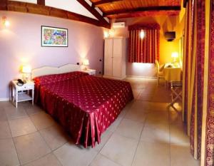 a bedroom with a large bed with a red bedspread at Hotel La Tortiola in Vigarano Mainarda