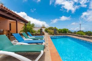 a pool with lounge chairs next to a house at Charming villa with sea view in Puntagorda in Puntagorda +14 photos