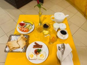a yellow table with plates of breakfast food on it at Sky Bello Hotel in Katunayaka