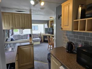 a kitchen with wooden cabinets and a living room at Seaside View Holiday Home in Aberystwyth