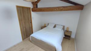 ein Schlafzimmer mit einem weißen Bett mit weißer Bettwäsche in der Unterkunft La tanière des trois Ogres, à 10min du Futuroscope in Beaumont