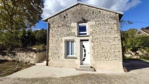 ein kleines Backsteingebäude mit einer weißen Tür in der Unterkunft La tanière des trois Ogres, à 10min du Futuroscope in Beaumont