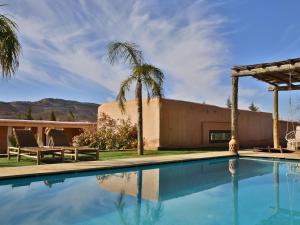 a swimming pool in front of a house with palm trees at L'Hacienda Joud - Privatisation de 5 chambres dans un havre de paix à Marrakech avec piscine & cuisinière privée dans le désert d'Aït Ourir in Aïn er Rmel