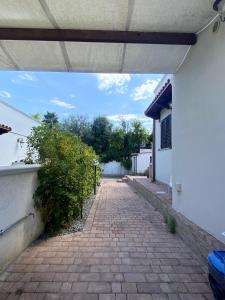 a brick walkway leading to a white building with a roof at Casa Vacanze - Villa Claudia in Leporano Marina