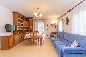 a living room with a blue couch and a table at Casa Erica in Falcade