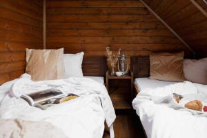two beds with white sheets in a room with wooden walls at Wild&Free Private Lake in Nagycsepely