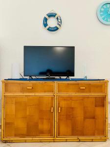 a television on top of a wooden cabinet with a clock at Elena's apartment in Cannigione