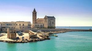 a large building with a clock tower next to the water at Dimora dAmare in Trani