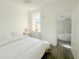 Dormitorio blanco con cama blanca y lavamanos en Pavilion - Beachfront Property, en Gorleston-on-Sea