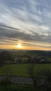 a sunset over a green field with the sun in the sky at Casa Vilamarín in Santa Eulalia