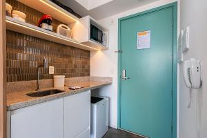 a kitchen with a sink and a blue door at Studio - Setin Downtown Estação Luz - Sou House in São Paulo