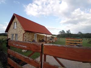 dom z czerwonym dachem na ogrodzeniu w obiekcie Fa Szamár Vendégház w mieście Demjén