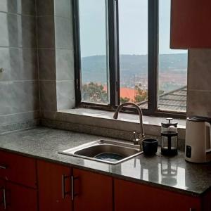 a kitchen counter with a sink and a window at Xenia house in Kigali