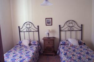 a bedroom with two beds and a table with a lamp at Casa Víctor in Priego de Córdoba