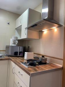 une cuisine avec des armoires blanches et un four à plaques de cuisson dans l'établissement Ático centro "El diván azul", à Malaga