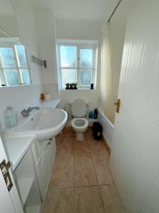 a white bathroom with a toilet and a sink at Luxury One-Bedroom House with Free Parking in Slough