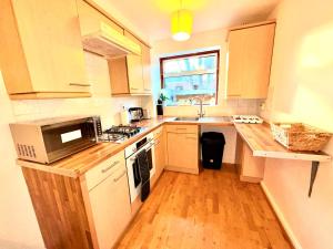 a kitchen with white cabinets and a sink and a microwave at Luxury One-Bedroom House with Free Parking in Slough