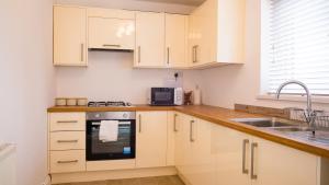 a kitchen with white cabinets and a sink at HouseSleeps6-Garden-Parking-Familly&Contractors in Walsall