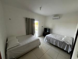 ein Schlafzimmer mit zwei Betten und einem Fernseher darin in der Unterkunft Casa Simões in Fortim