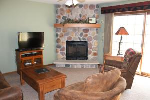 un salon avec une cheminée en pierre et une télévision dans l'établissement Wild Eagle Lodge, 1 Bedroom Condo - 103, à Eagle River