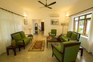 ein Wohnzimmer mit grünen Möbeln und einem Deckenventilator in der Unterkunft Beach Gate Bungalows - CGH Earth in Kochi