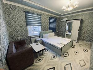 a room with a bed and a chair and a table at Samandar in Bukhara
