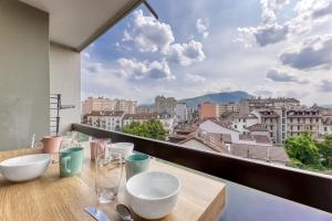 a table with bowls and glasses on a balcony with a view at La Boisée in Annemasse