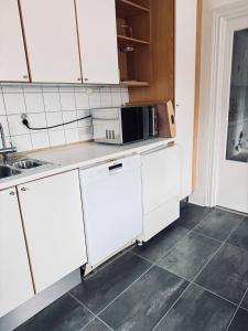a kitchen with white cabinets and a microwave at Spacious flat for large group in Stockholm